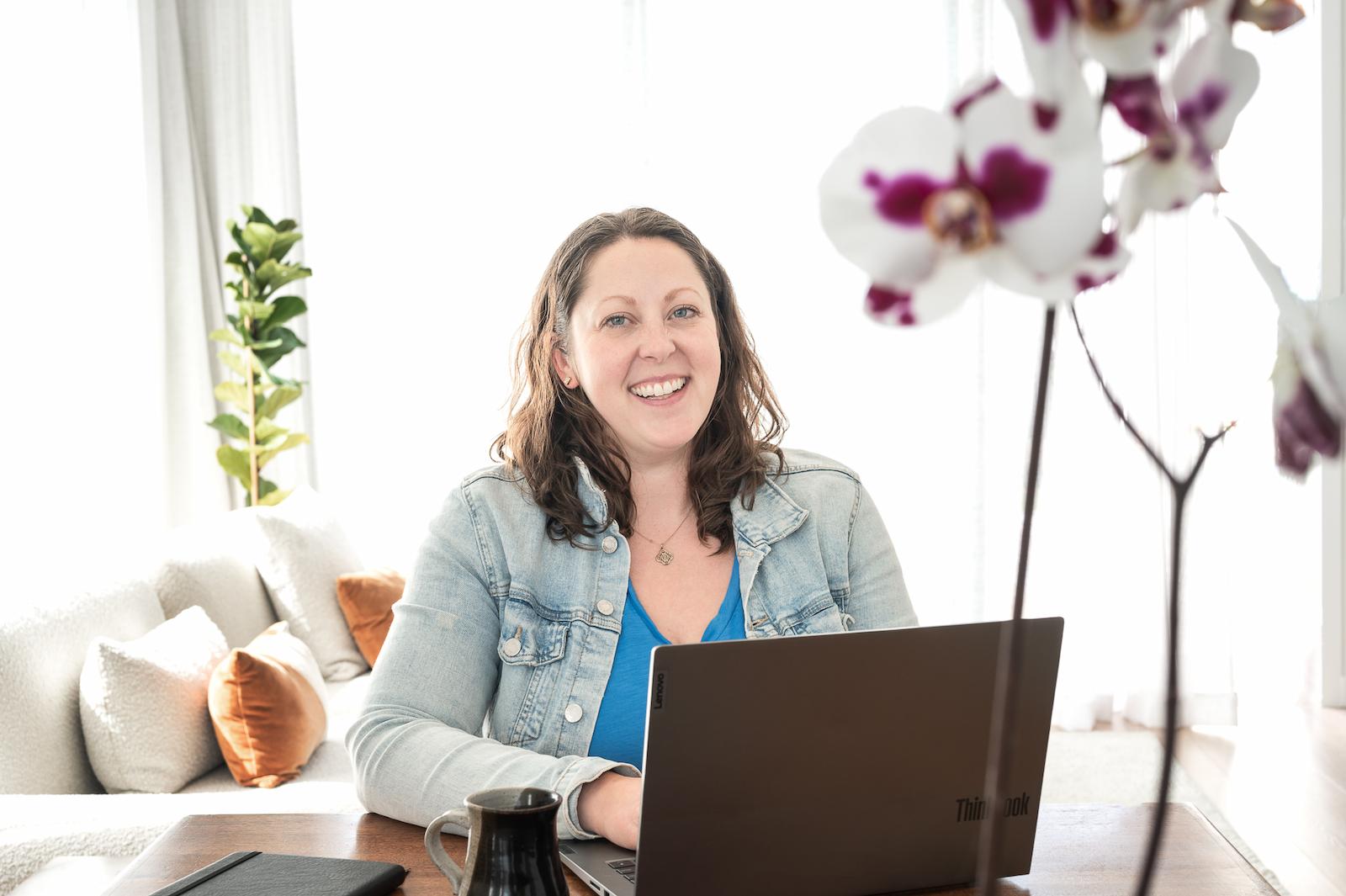Image of a woman working on her laptop, with flowers